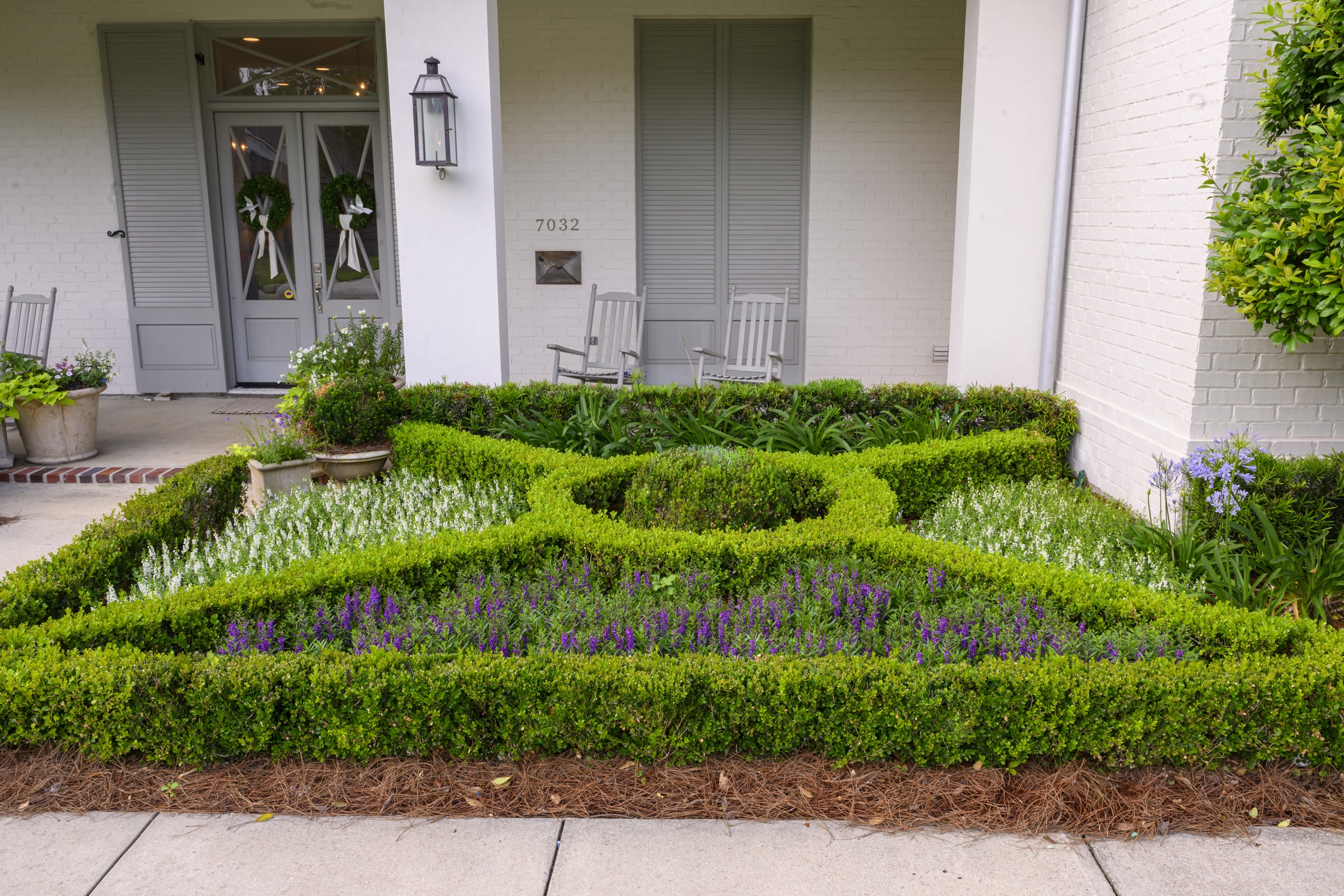 Knot garden in bloom in front of the gray porch doors