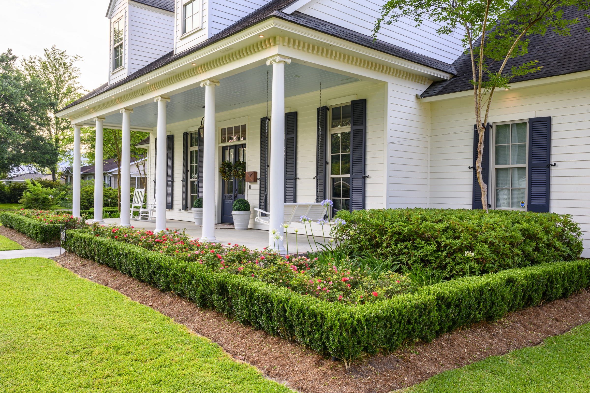 Full porch frontage with column rhythm and trimmed boxwood