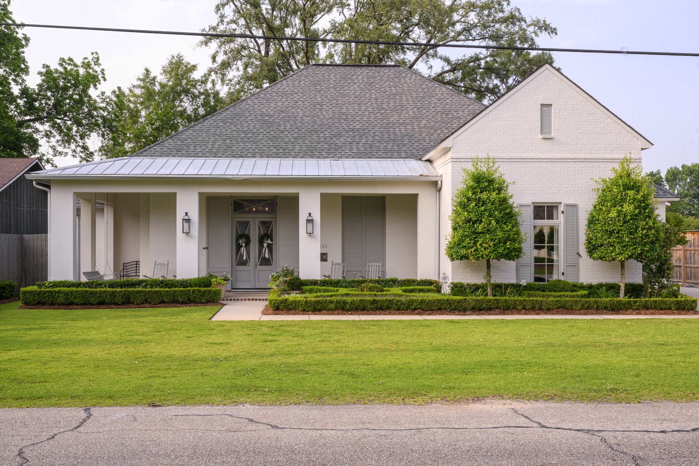 White cottage with metal roof and crepe myrtles