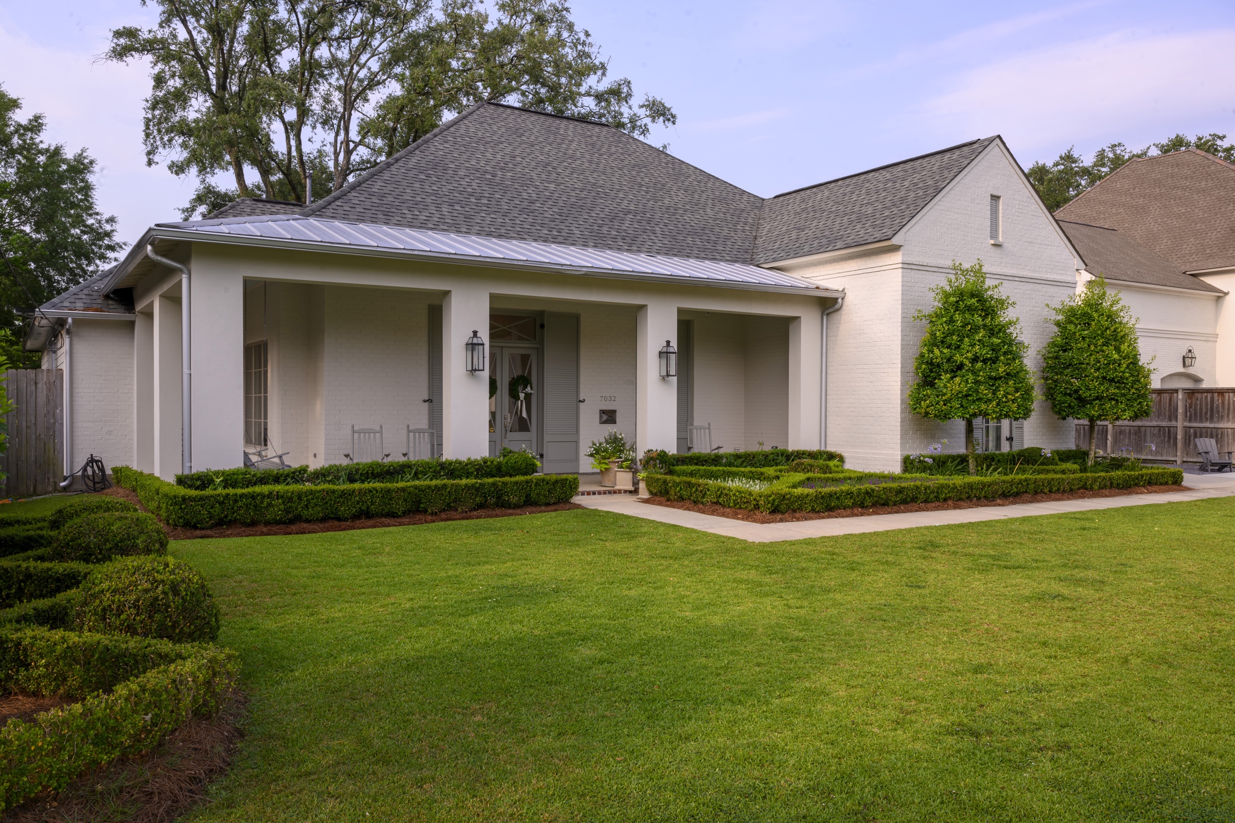 White cottage frontage with formal boxwood beds