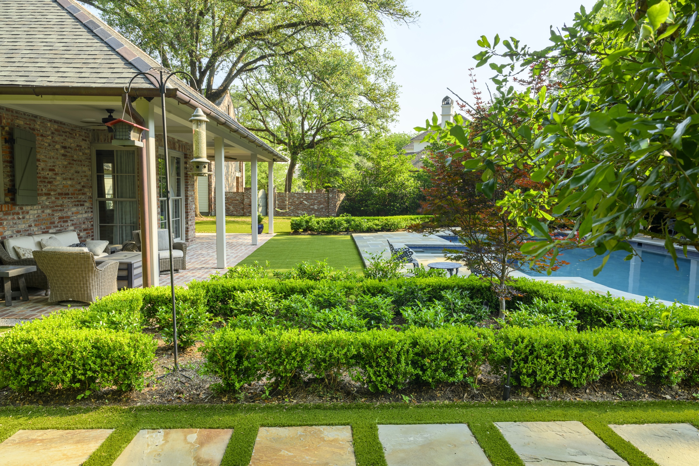 Brick garden house with formal boxwood ring and pool beyond