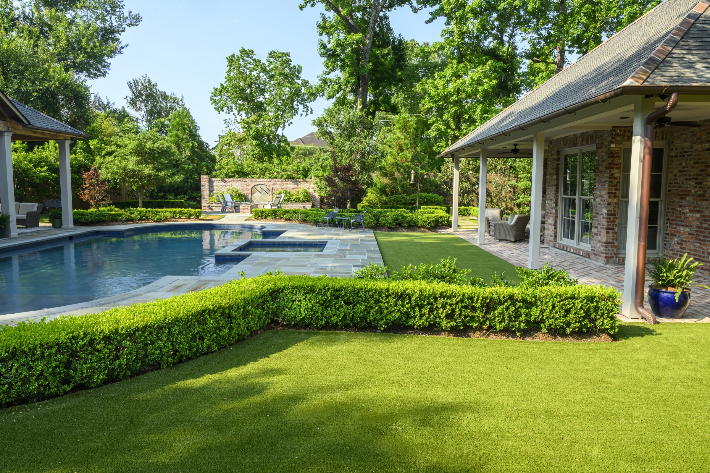 Pool and stone surround framed by trimmed boxwood