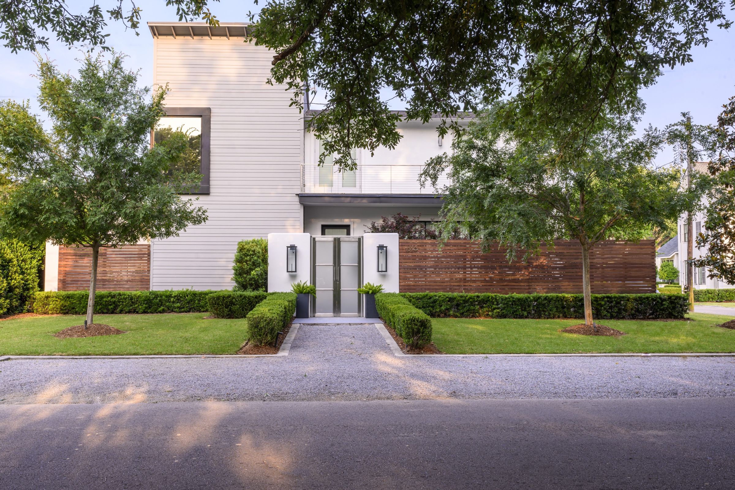 Modern home front with shade trees and sculpted hedges